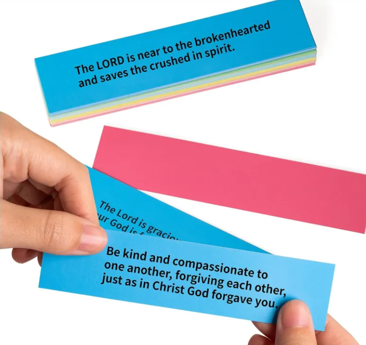 Colorful strips of paper with inspirational quotes held by a hand on a white background