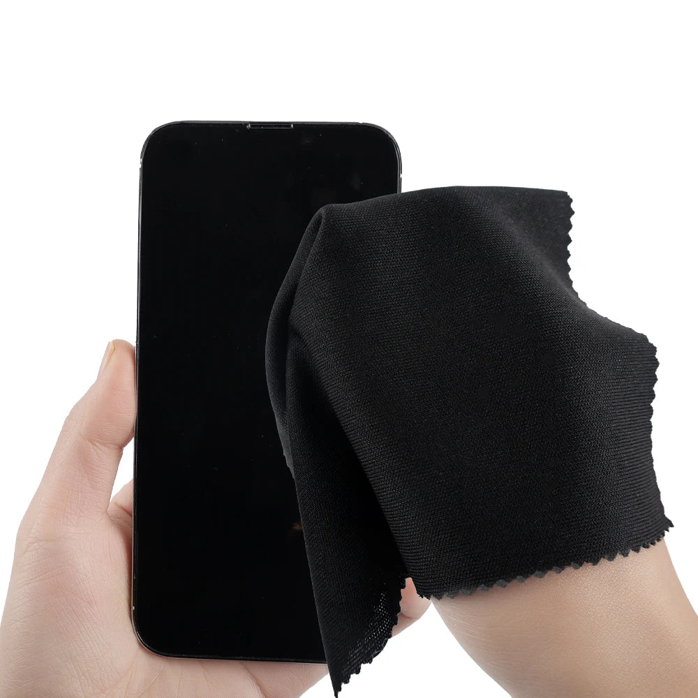 Person holding a black smartphone and a black cleaning cloth on a white background